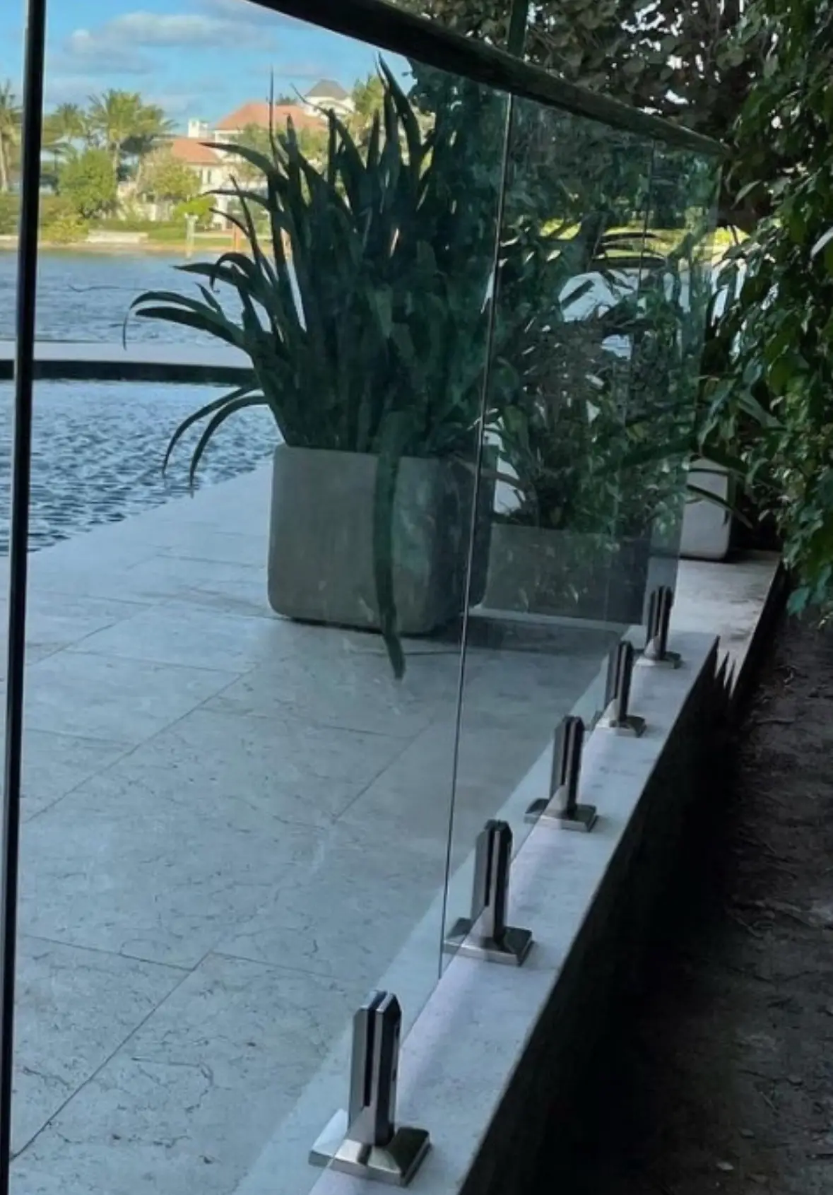 Frameless glass railing on spigots beside a backyard pool